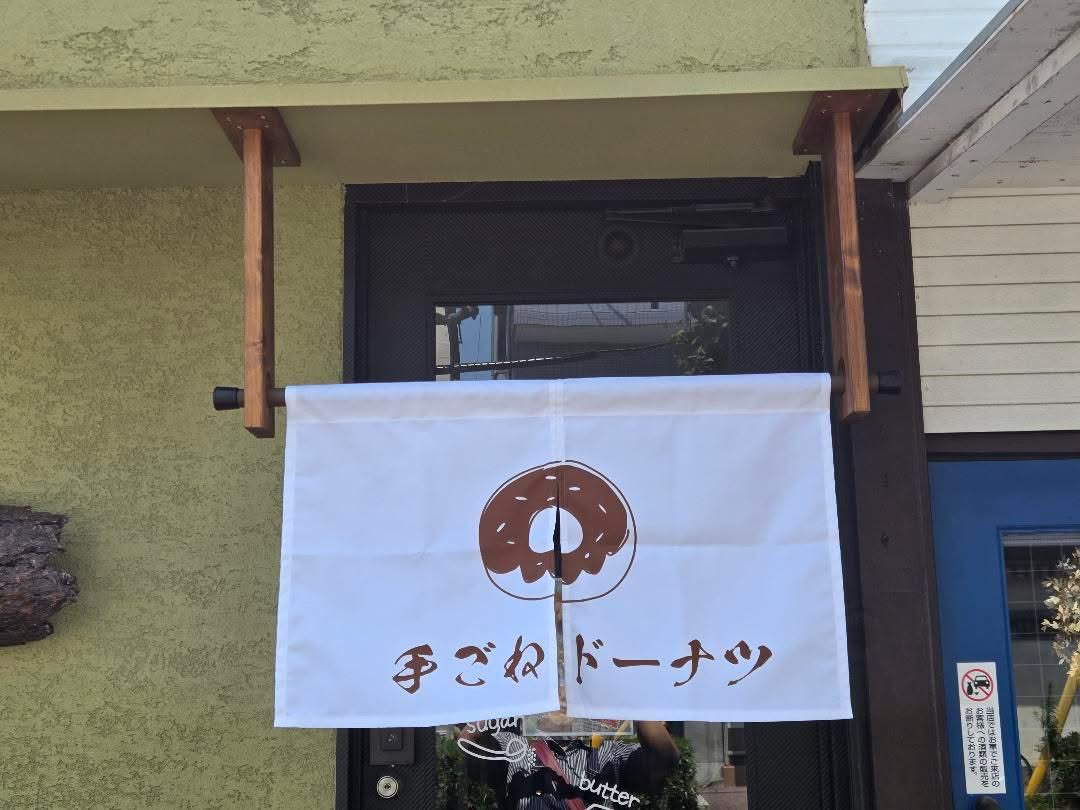 白いのれんに手ごねドーナツと書かれた Marumi Kitchen Nico の店頭